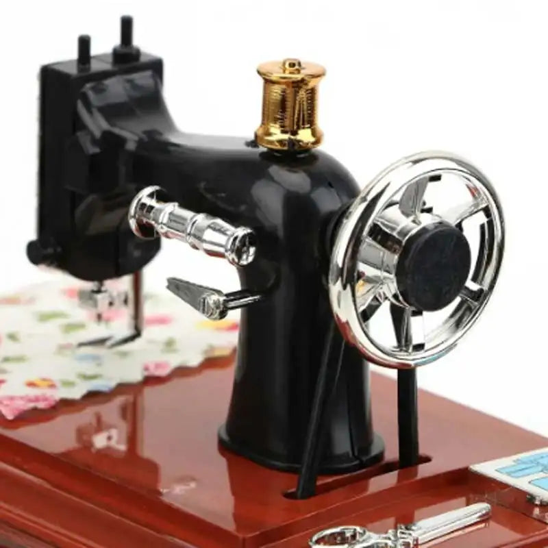 A vintage sewing machine music box decorative ornament in black with a brass spindle top.