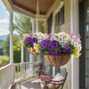 A hanging basket filled with artificial pansy flowers in purple, white, and yellow hues on a porch.