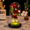 A glass dome display featuring a red rose and green moss, illuminated by small LED lights.