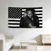 A black and white tapestry banner featuring the American flag design with a person's face superimposed.