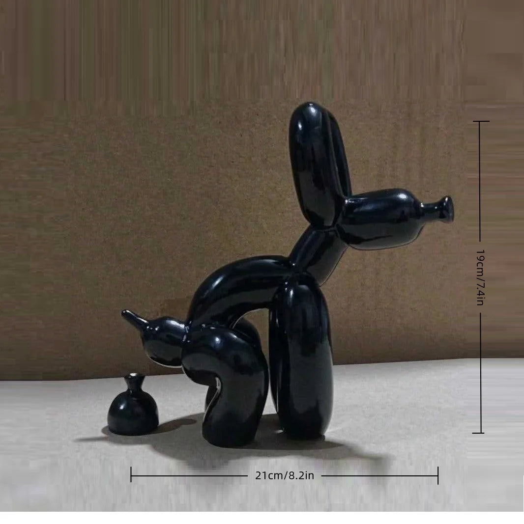 A black, stylized sculpture of a dog squatting, displayed on a light surface.