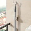 A silver wall mounted holder for a mop and broom, attached to a light-colored wall.