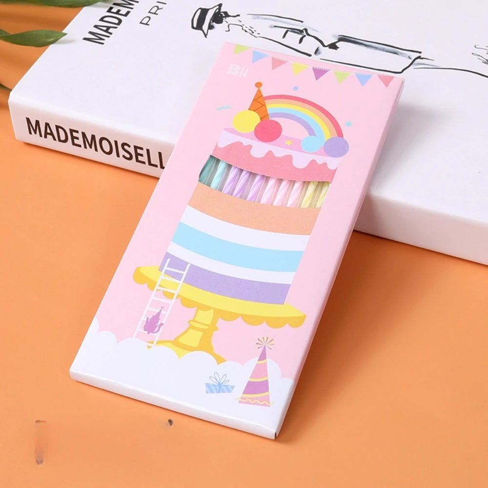 A pink and white box of elegant spiral cake candles featuring a tiered cake design with rainbow decorations.