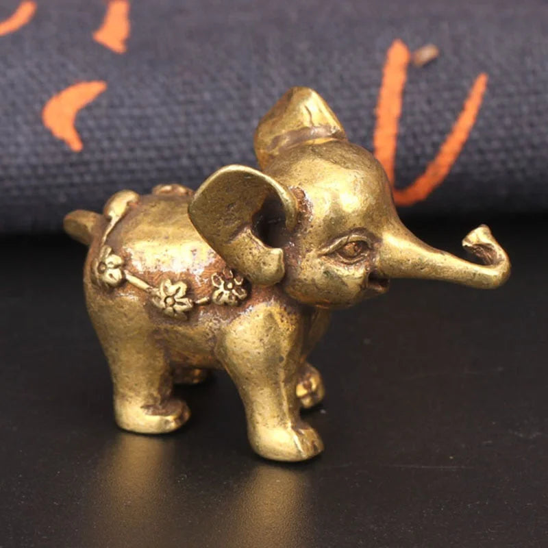 A small antique bronze elephant figurine with a textured surface, resting on a dark background.