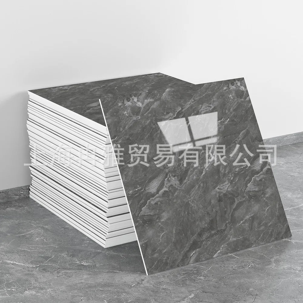 A rectangular slab of dark gray faux marble material is shown next to a stack of white tiles, demonstrating the peel-and-stic