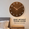 Minimalistische runde Holzwanduhr mit goldenen Akzenten, montiert über einem Bett.