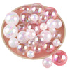 A collection of pink and iridescent pearl-like spherical balloon cake toppers arranged on a round plate.