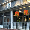 Artificial hanging morning glory flowers in vibrant orange and yellow with eucalyptus leaves displayed on a porch.
