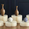 Présentation de vases en céramique blanc et marron et d'un support alimentaire en acrylique blanc sur une table en bois.