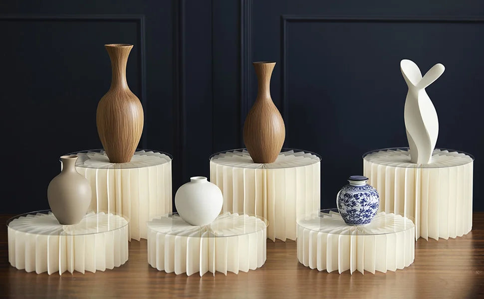 Présentation de vases en céramique blanc et marron et d'un support alimentaire en acrylique blanc sur une table en bois.