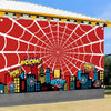 A large banner featuring a red spiderweb design over a cityscape with buildings and colorful text like BOOM WOW POW