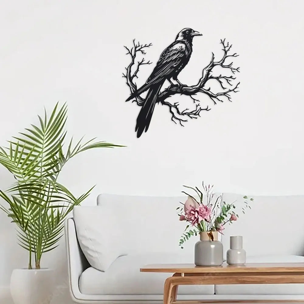 Black raven perched on a bare tree branch metal wall art displayed above a white sofa.