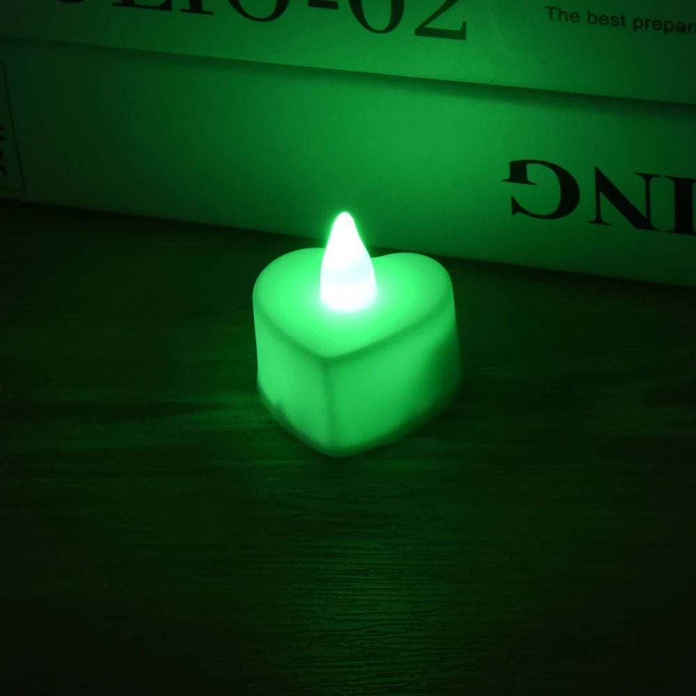 A glowing green heart-shaped LED tealight candle resting on a dark wooden surface.