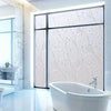 A modern bathroom featuring a glass shower enclosure and a white bathtub with frosted electrostatic window film.
