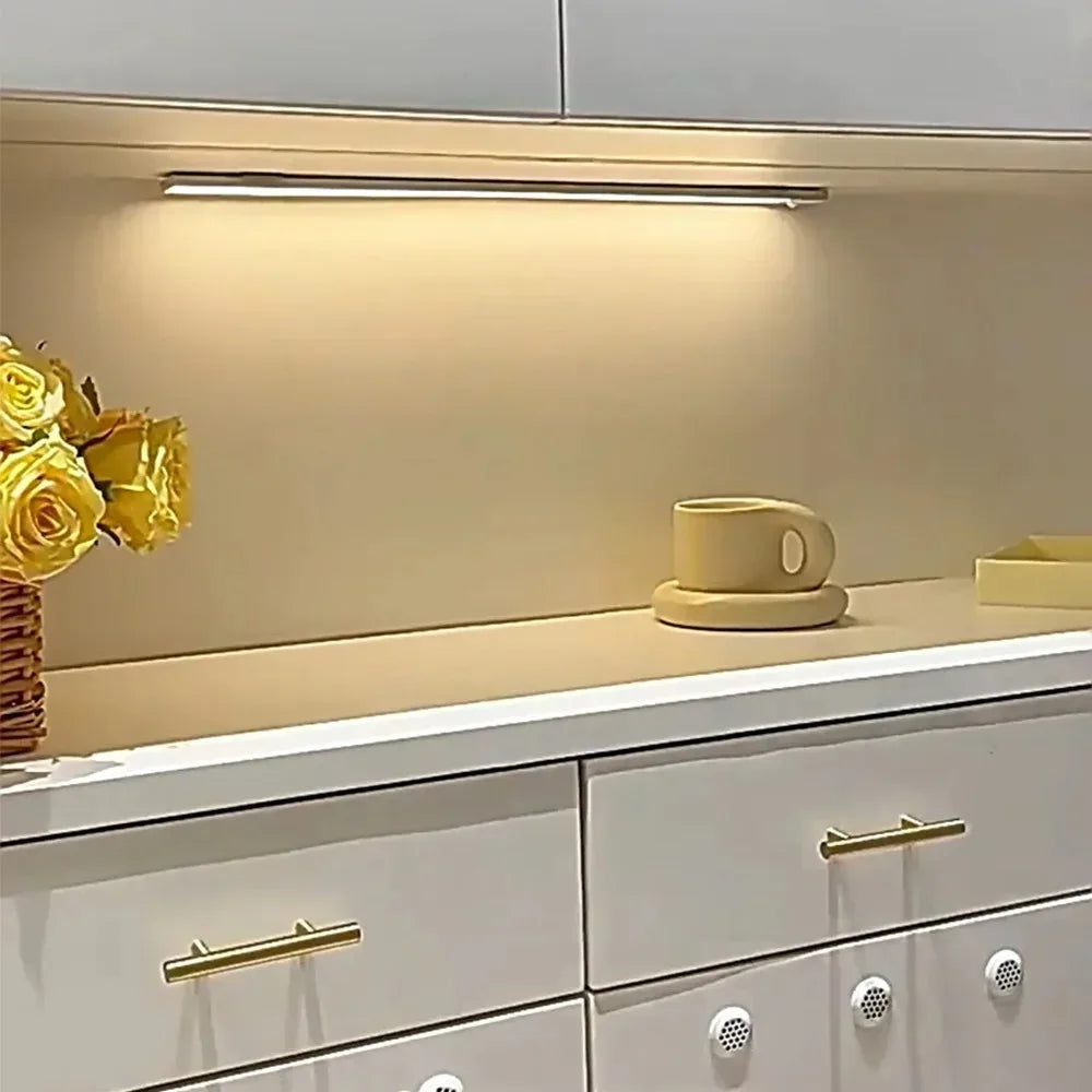 Under-cabinet lighting illuminates a countertop with a yellow flower and a ceramic cup in a modern kitchen cabinet.