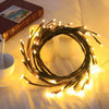 A circular arrangement of warm white LED vine string lights illuminates a soft background with candles and a book.