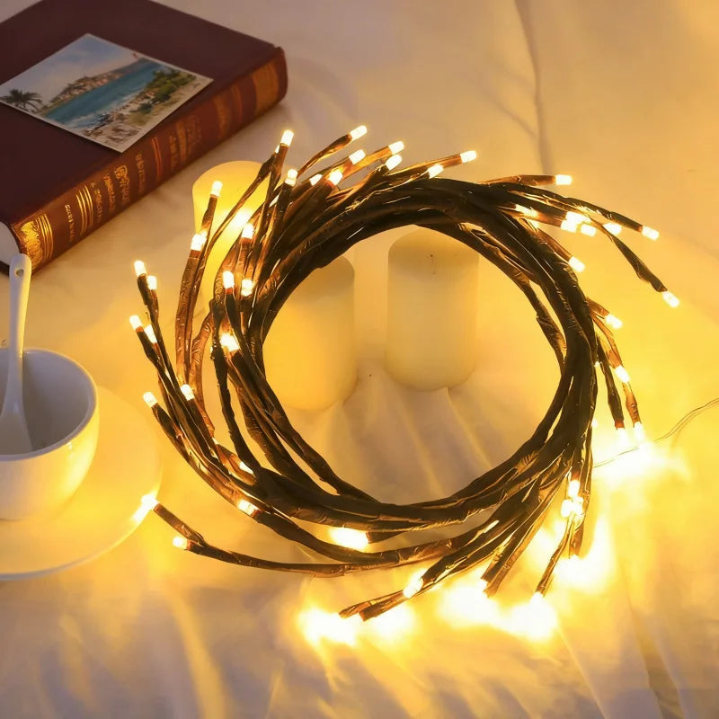 A circular arrangement of warm white LED vine string lights illuminates a soft background with candles and a book.