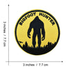 Yellow embroidered patch with black text Bigfoot Hunter on an oval shape