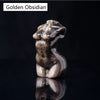 Figura esculpida y brillante de una figura femenina hecha de Obsidiana Dorada, reflejando la luz.