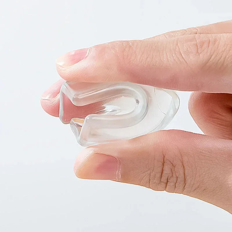 A hand holds a clear silicone corner protector designed for baby safety.