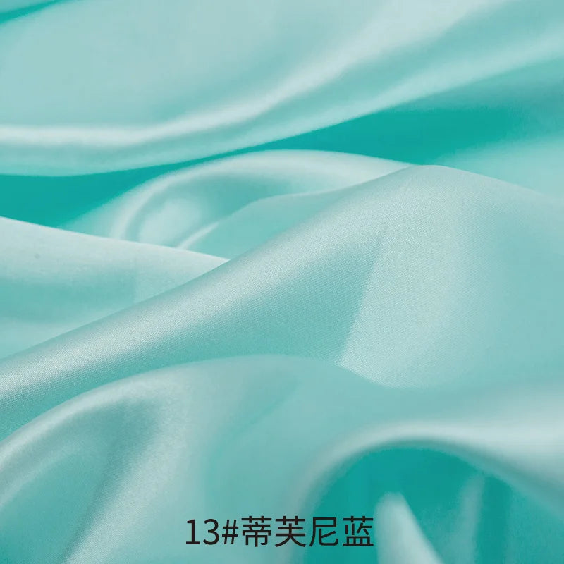 Light mint green satin fabric draped and folded for sewing or DIY projects