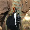 A black glove clip holder is attached to a tan tactical vest, featuring an orange clip and a black bottle.