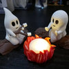 Halloween ghost figures sitting on a dark surface next to a glowing orange campfire decor set