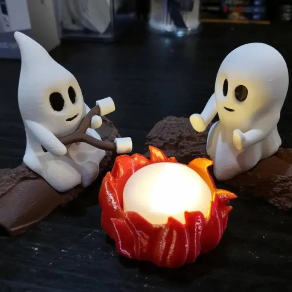 Halloween ghost figures sitting on a dark surface next to a glowing orange campfire decor set