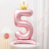 A pink foil number balloon shaped like the number 5 with a gold crown on top