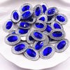A pile of round, brilliant blue gemstone flatback rhinestones set in silver-toned metal.