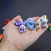 A hand holds several colorful, poseable 3D printed animal figurines including purple and white characters.