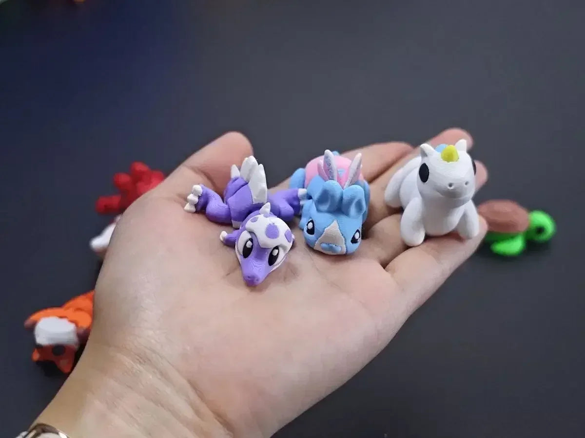 A hand holds several colorful, poseable 3D printed animal figurines including purple and white characters.