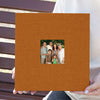 A brown linen scrapbook with a square opening displaying a photo of a multi-generational family.
