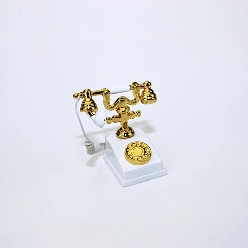 A vintage rotary desk phone miniature decor featuring brass-colored receiver and base on a white stand.