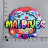A colorful fridge magnet featuring dolphins and the word Maldives on a wooden background.