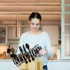 A woman is holding a cardboard box with decorative metal sign art for a farmhouse kitchen.