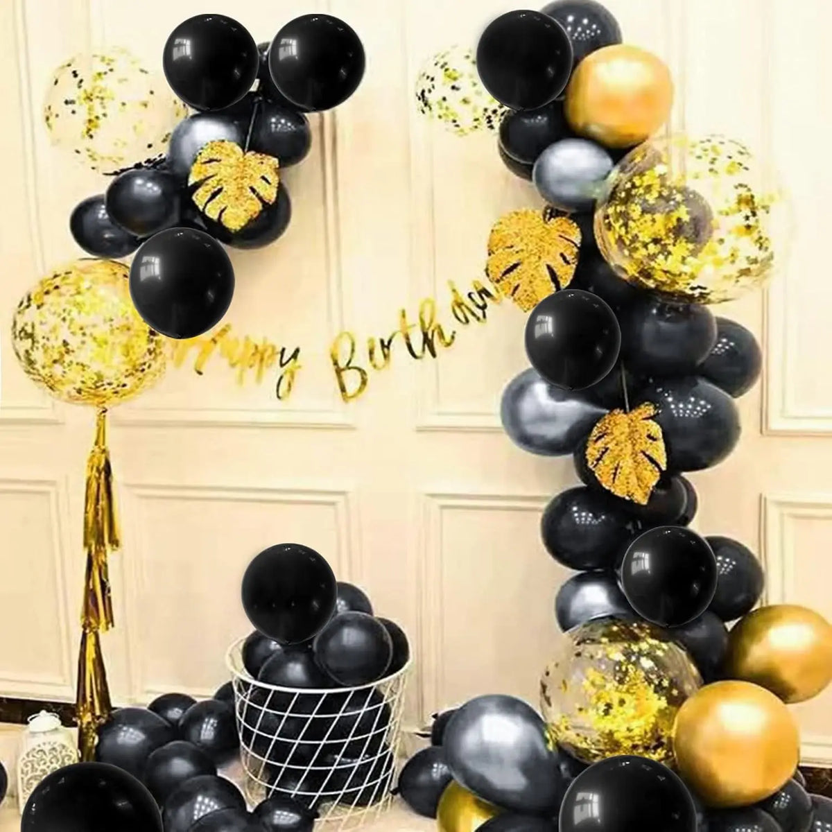 A display of black and gold latex balloons arranged in a heart shape for a birthday celebration.