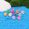 A collection of glow-in-the-dark Christmas duck figurines wearing Santa hats scattered on bright blue material.