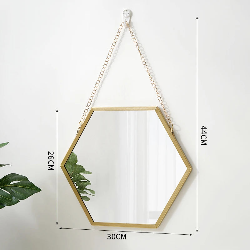 A hexagonal wall mirror with a gold frame and a chain hanger, shown against a white background.