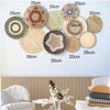 A collection of round boho straw wall hangings in various sizes and shades displayed against a light blue wall.
