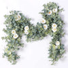 A lush garland of silvery-green eucalyptus leaves and white roses used for floral decoration.