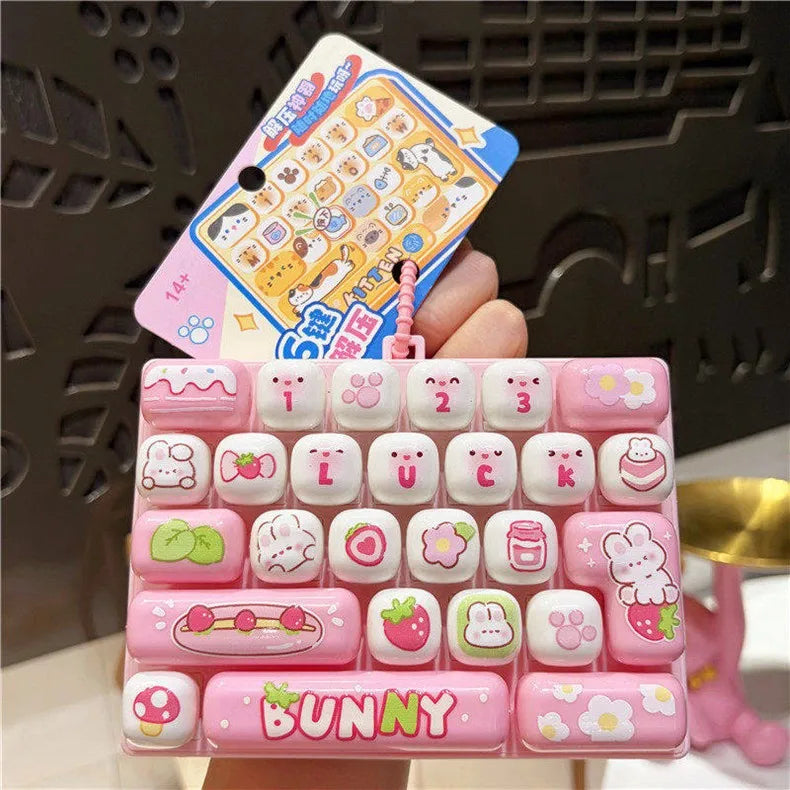 A pink acrylic keyboard keycap keychain featuring various cartoon animal designs like a bunny and other cute characters.