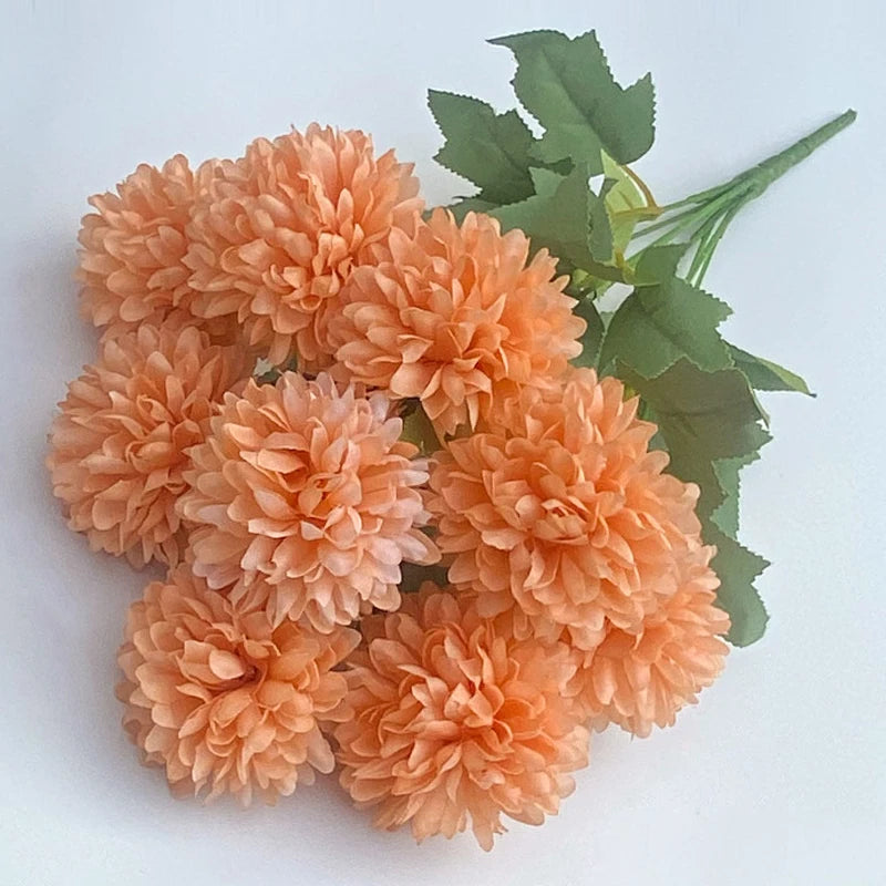A bouquet of artificial orange hydrangeas and green camellia leaves.