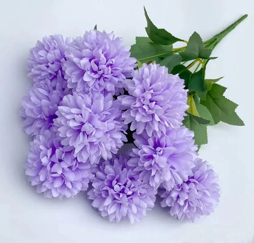 A bouquet of artificial lilac hydrangea flowers and green camellia leaves.