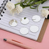 White floral arrangement and several round silver mirror decals placed on a lined notebook.
