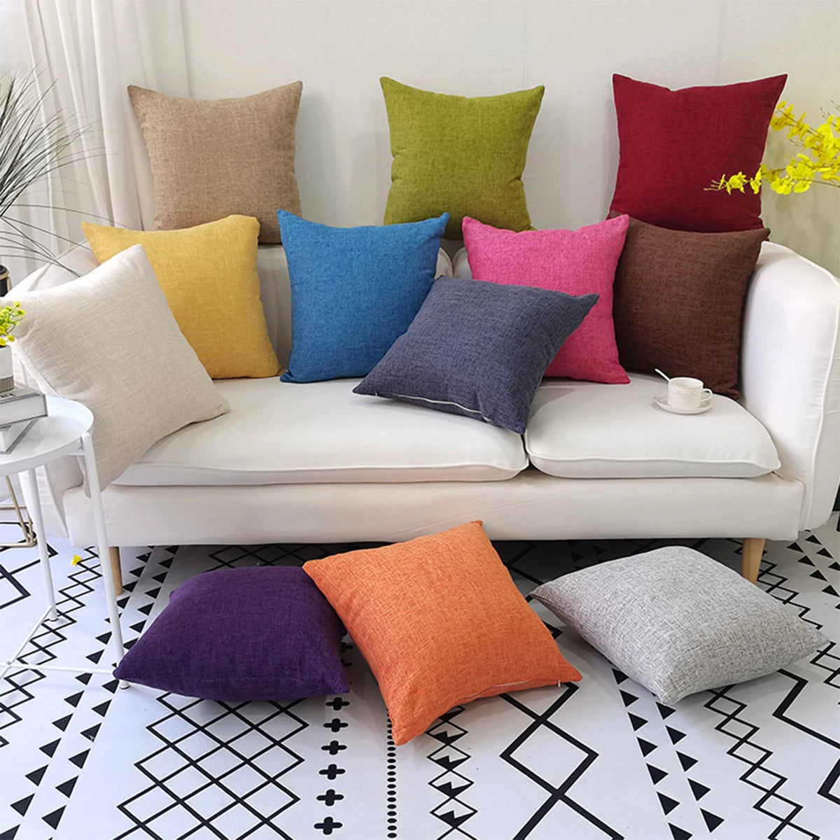 A collection of colorful linen pillows in shades of yellow, green, blue, pink, and terracotta arranged on a white sofa.