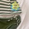 A close-up of a striped sleeveless top featuring a yellow floral print on the chest, laid flat on a white surface.