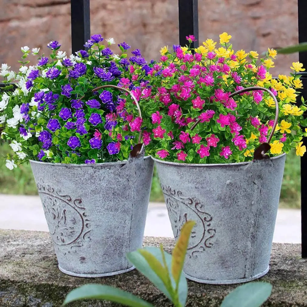 Two galvanized pots filled with vibrant faux floral plants featuring purple, pink, and yellow blooms.