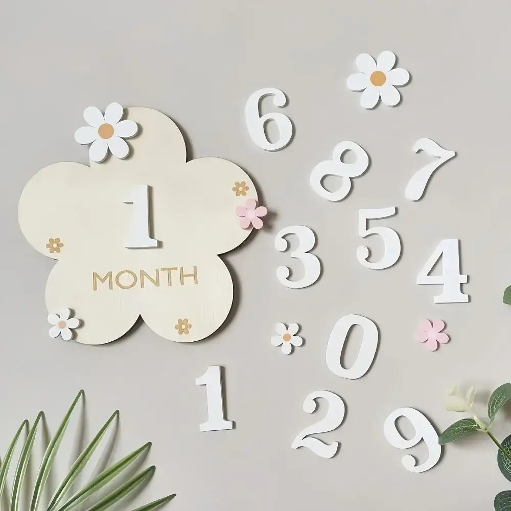 A collection of wooden monthly milestone cards featuring numbers and flowers on a light gray background.