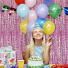 Eine junge Frau lächelt und hält einen Ballonstrauß vor einem pinken Tinsel-Hintergrund für eine Veranstaltung.